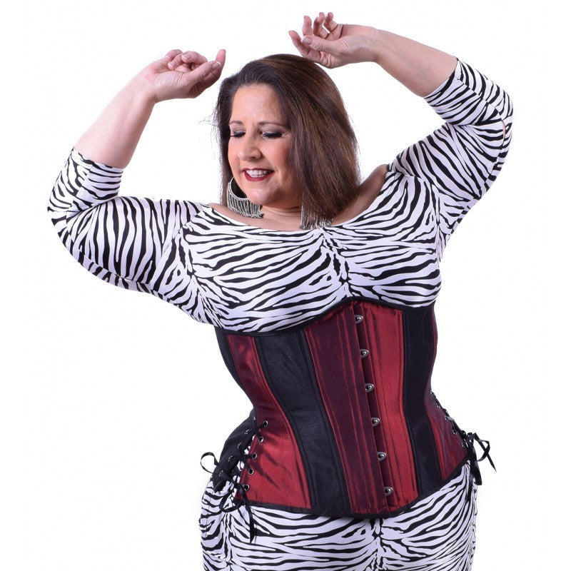 Iridescent red taffeta corset with insert panels of black taffeta, hourglass silhouette, long length with adjustable side hip lacing, on a model who styled it with a zebra print dress