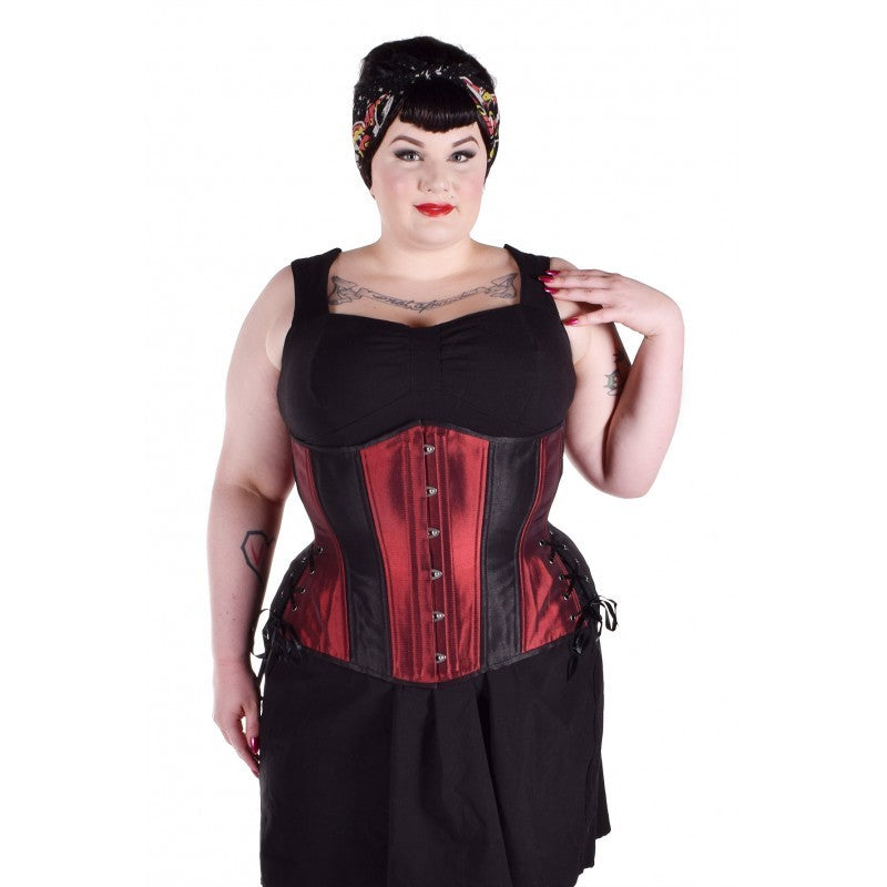 Iridescent red taffeta corset with insert panels of black taffeta, hourglass silhouette, long length with adjustable side hip lacing, on a model who styled it with a black dress and head scarf